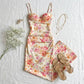 Roselle floral satin slip dress in cream with vintage rose print and corset bust, styled flat lay with beige sandals and gold jewelry.