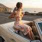 Roselle floral satin slip dress in cream with vintage rose print, featuring a corset-style bust and spaghetti straps in a sunset setting.