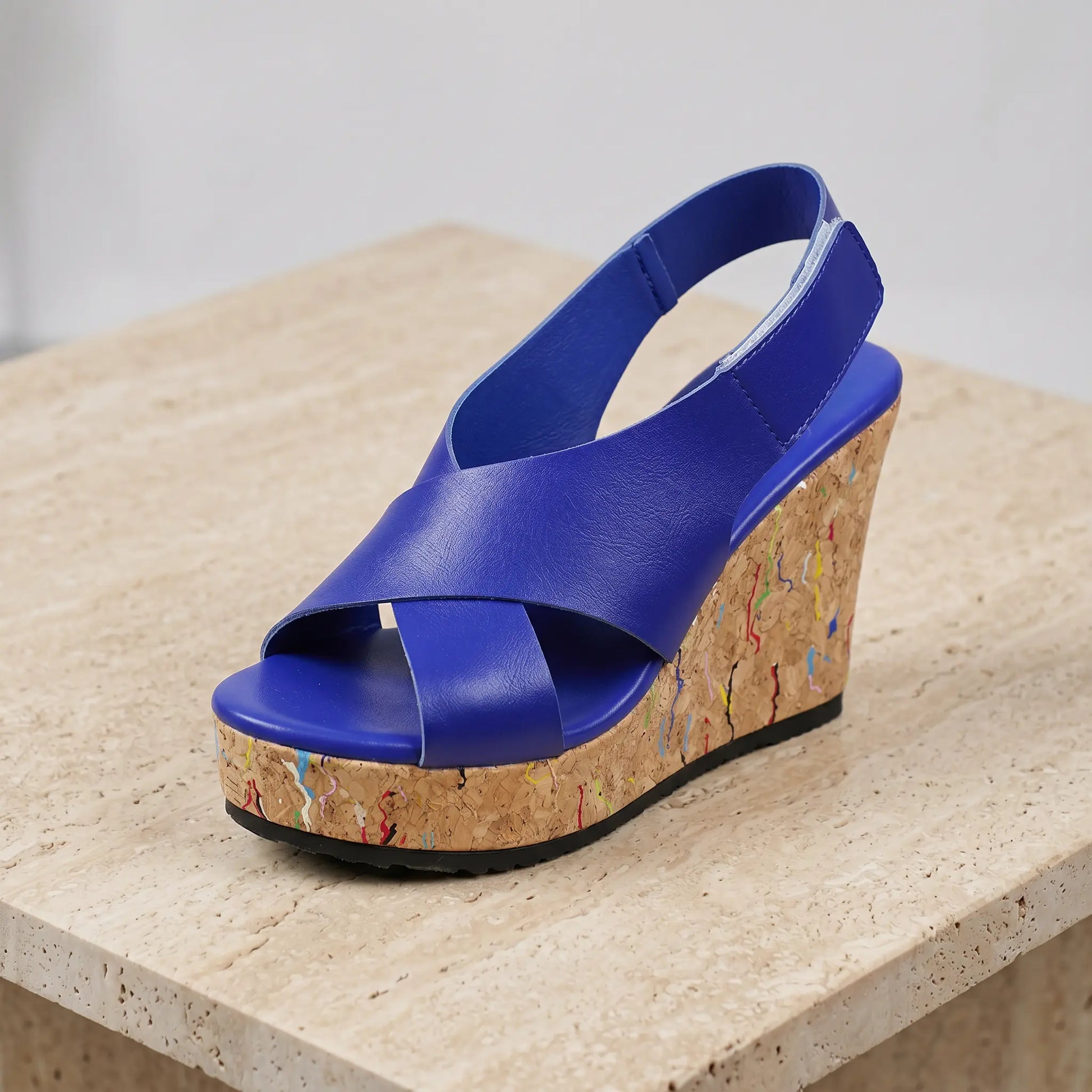Royal blue women's platform wedge sandal with criss-cross faux leather straps and a cork-effect sole speckled with multi-colour flecks.