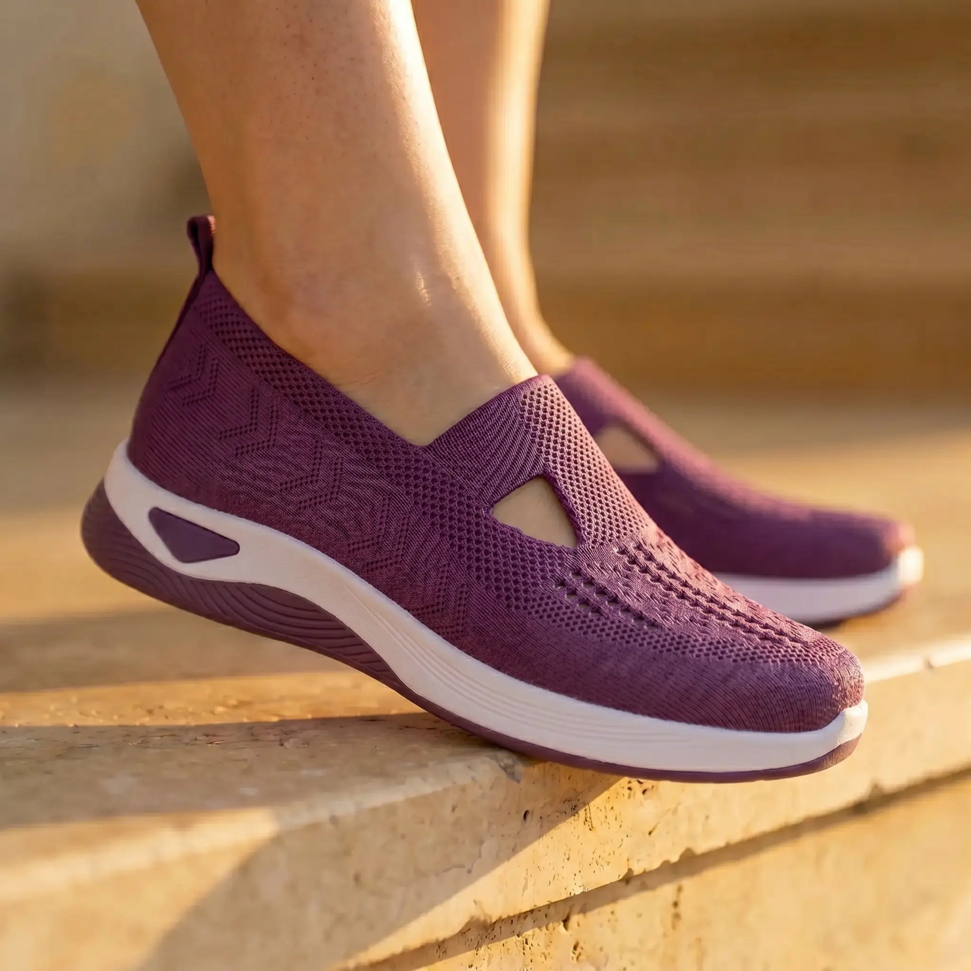 Amethyst purple Ruxen slip-on sneakers worn by a person on sunlit stone steps, showcasing the breathable woven knit upper with diamond perforations and triangular cutout, atop a white platform sole.
