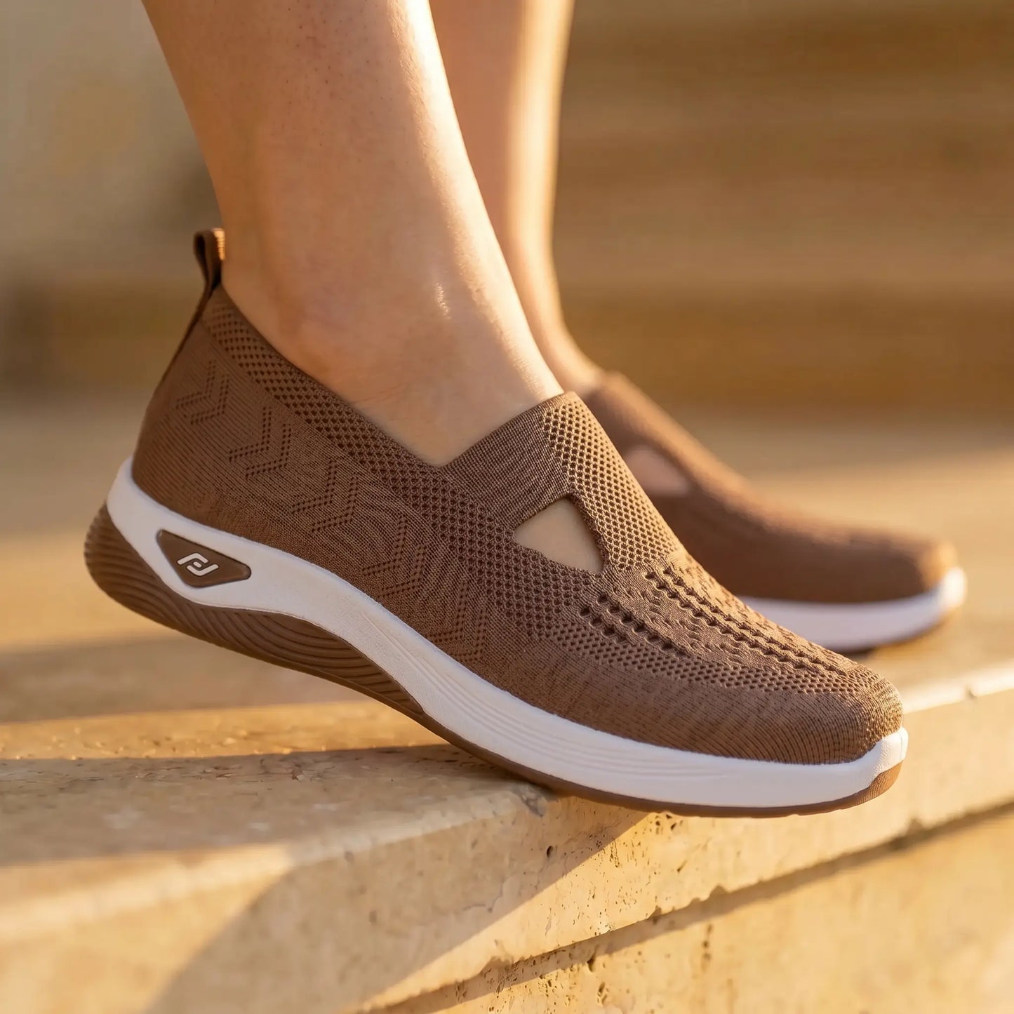 Person wearing Ruxen Rich Mocha woven knit slip-on sneakers with triangular cutout, diamond perforations, and white platform sole on stone steps.
