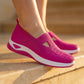 Vibrant rose Ruxen women's slip-on sneakers with breathable knit upper and thick white sole, worn on sunlit stone steps.