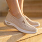 Woman wearing Ruxen warm beige knit slip-on sneakers with triangular cutout and diamond toe perforations, standing on sunlit stone steps.