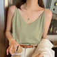 Sage green ribbed V-neck camisole with thin straps, worn by a woman accessorized with layered pearl and gold necklaces in a lifestyle setting.
