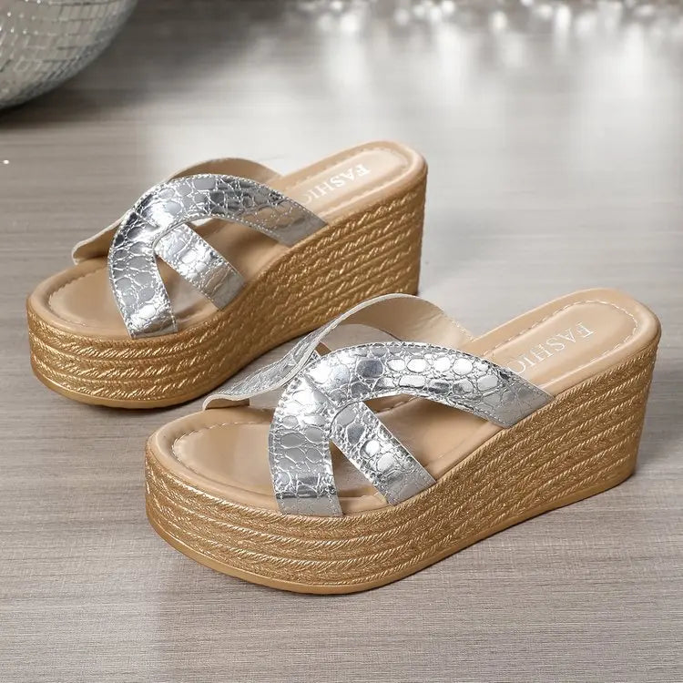 Silver cracked metallic leather espadrille wedge sandals with a criss-cross strap design and platform sole, shown from a three-quarter angle on a wooden surface.
