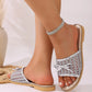 Silver mesh bow slide sandal on a model's foot, showcasing its elegant design with a delicate bow accent and braided sole trim. The open-toe sandal features a shimmering metallic finish and is styled with a crystal anklet.