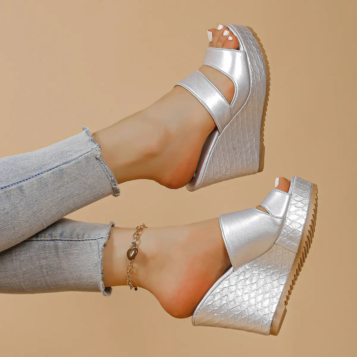 Silver peep-toe platform wedge sandals with intersecting straps and snake-effect textured heel and sole, worn with distressed jeans.