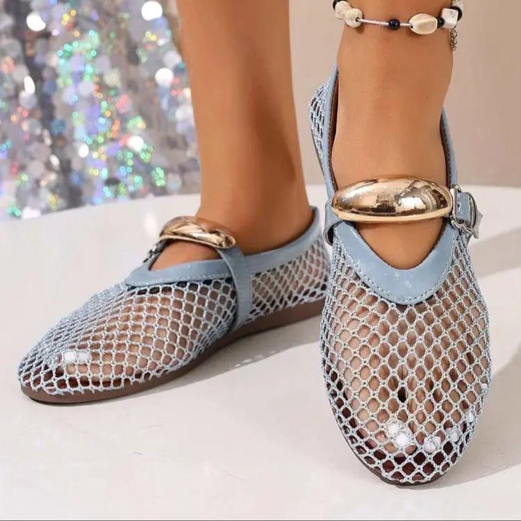 Light blue Solarae mesh flat sandals with decorative gold oval buckle strap, shown on feet with a sparkling background. These elegant casual footwear pieces offer breathability and chic comfort.
