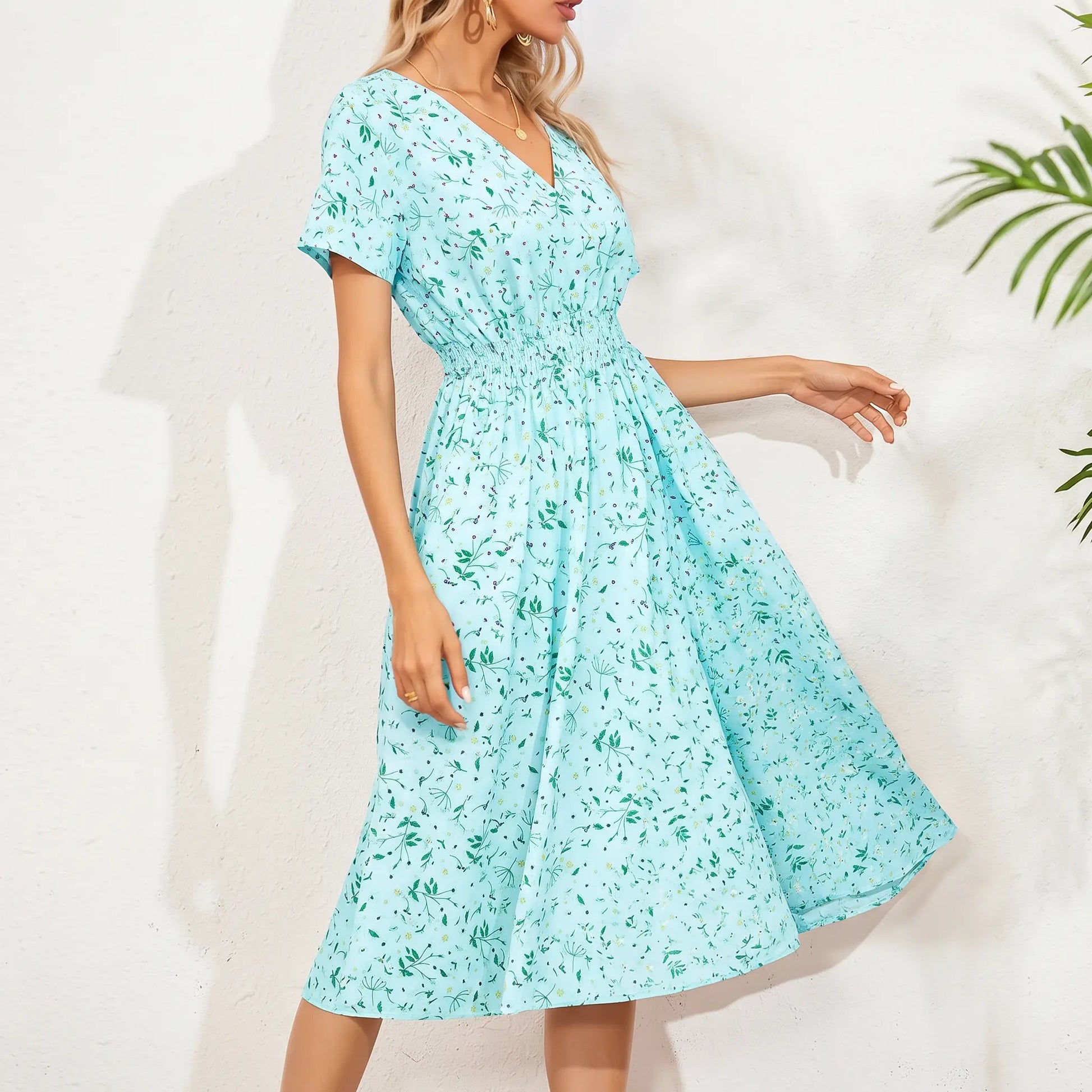 A women's light blue ditsy floral print midi dress with a V-neck, smocked waistband, and short flutter sleeves, shown on a model with a white textured background and shadow play.