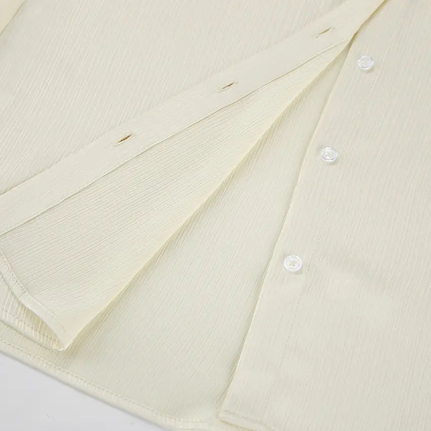 Close-up of the cream crinkle-pleated shirt from the Tarkem two-piece set, highlighting the vertical texture and clear tonal button placket.