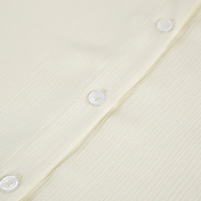 Close-up of the Tarkem ivory buttercream two-piece set, highlighting the exquisite micro-pleated fabric texture and tonal button placket.