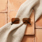 Tavren vintage square sunglasses with gilded gold ultra-thin metal frames and rich brown lenses, artfully arranged on a light beige linen cloth over rustic terracotta tiles.