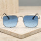 Tavren vintage square sunglasses with sleek silver metal frames and gradient azure blue lenses. Front view, showing thin temples and black ear tips, resting on a textured studio surface.