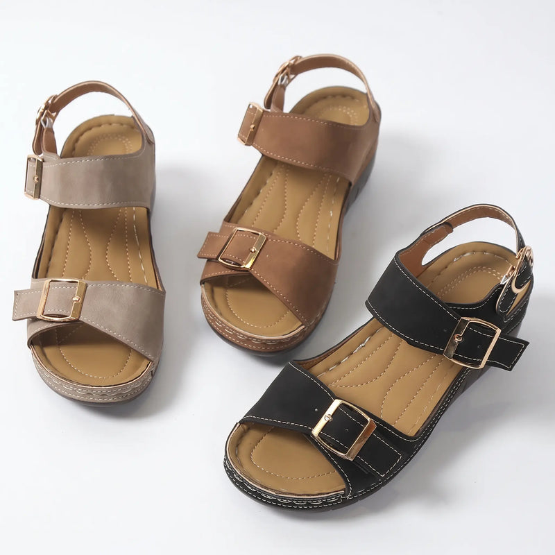 Three pairs of Torvin wedge sandals shown in black, tan, and brown faux suede with gold buckle details on a white background.