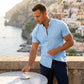 Vandore men's light blue mandarin collar shirt in linen-weave texture, worn by a model on a coastal terrace during summer vacation.