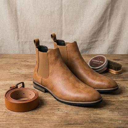 Vantor Classic Chelsea boots for men in burnished tan microfiber leather, styled on a wooden surface with a matching belt and care wax.