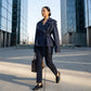 Varelle structured short trench coat in navy blue worn belted in an urban setting — front view showing the oversized lapels and cinched waist.