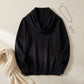 Vellura soft cowl neck sweater in black, flat lay view styled with silver jewelry and a beige scarf.