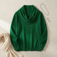 Vellura soft cowl neck knit sweater in emerald green, flat lay view showing the draped neckline and ribbed cuffs styled with silver accessories.