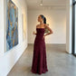 Veloura burgundy jacquard maxi dress with cowl neckline and textured floral pattern, modeled in an elegant art gallery setting.