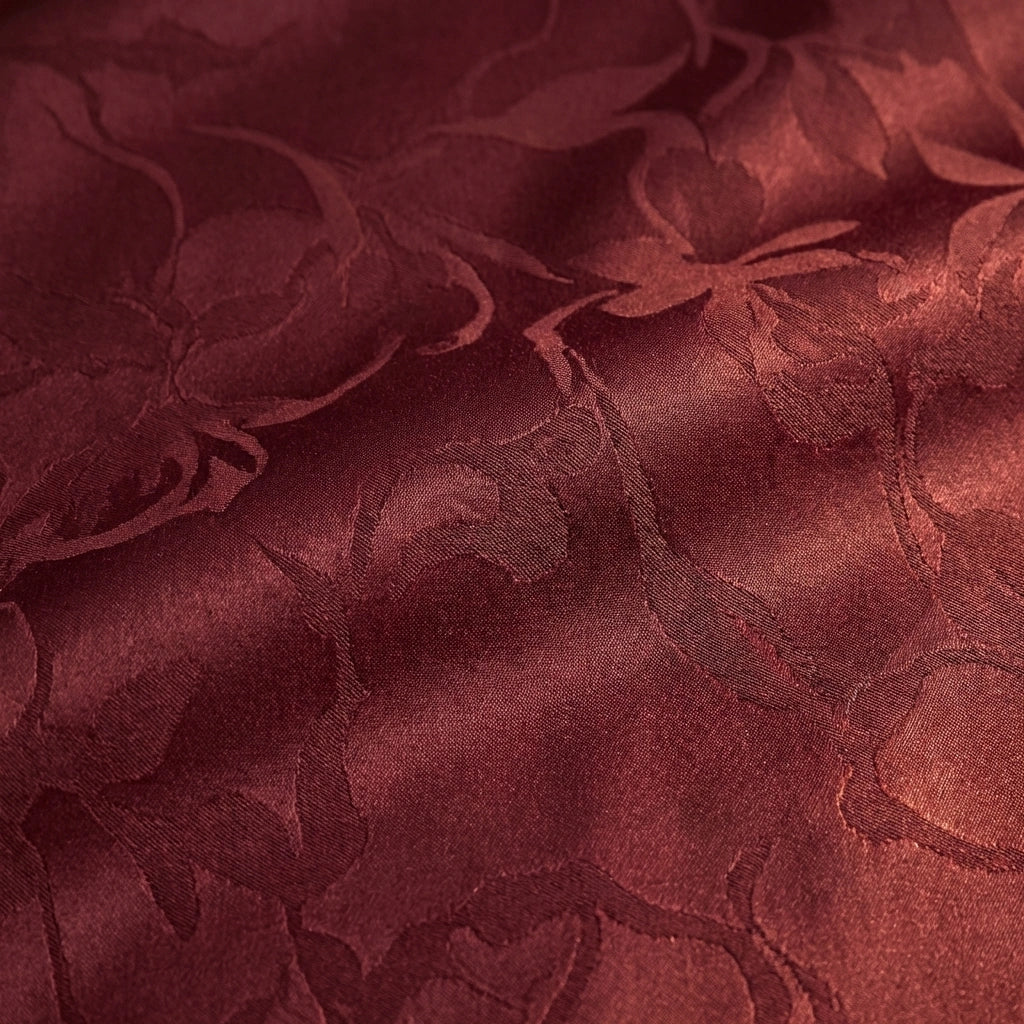 Close-up view of Veloura burgundy jacquard fabric texture showing the raised floral relief pattern and subtle sheen.