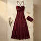 Veloura burgundy jacquard maxi dress flat-lay on stone surface, showing cowl neckline and floral texture styled with evening accessories.
