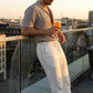Ventoso men's linen trousers in ivory cream worn in a sunset rooftop setting, showing the relaxed straight-leg fit and adjustable drawstring waist.