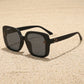 Oversized square black sunglasses with gradient grey lenses and gold floral accents on the temples. Presented on a clean white background.