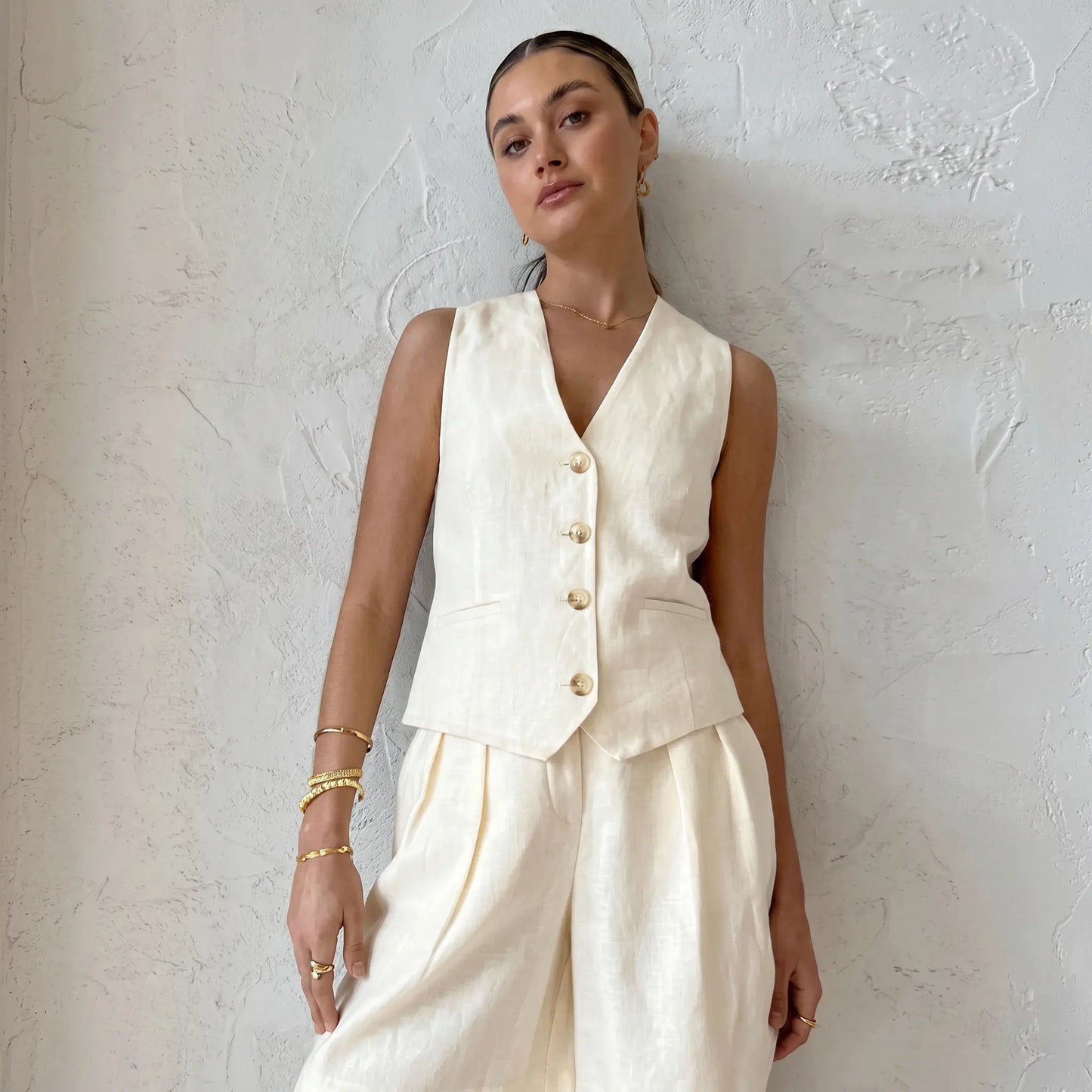 Women's Vorien chic linen blend summer set in warm ecru, featuring a sleeveless tailored vest with mother-of-pearl buttons and wide-leg pleated shorts, shown on a model in a studio.