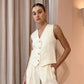 Vorien women's chic linen blend set in creamy ecru, featuring a sleeveless V-neck vest with mother-of-pearl buttons and high-waisted, wide-leg pleated shorts with cuffed hems, shown on a model.