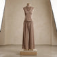 Vorlag taupe V-neck sleeveless flowy resort set with wide-leg trousers on a mannequin, showcasing its fluid drape and relaxed silhouette. This elegant two-piece is styled with a delicate necklace.