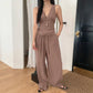 A woman models a two-piece taupe resort set featuring a sleeveless V-neck top with gathered bust and flowy wide-leg trousers with an elastic drawstring waist.