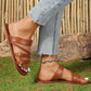 Vorlag women's brown braided strap summer slide sandals worn with distressed denim jeans and a turquoise anklet in a natural outdoor setting.