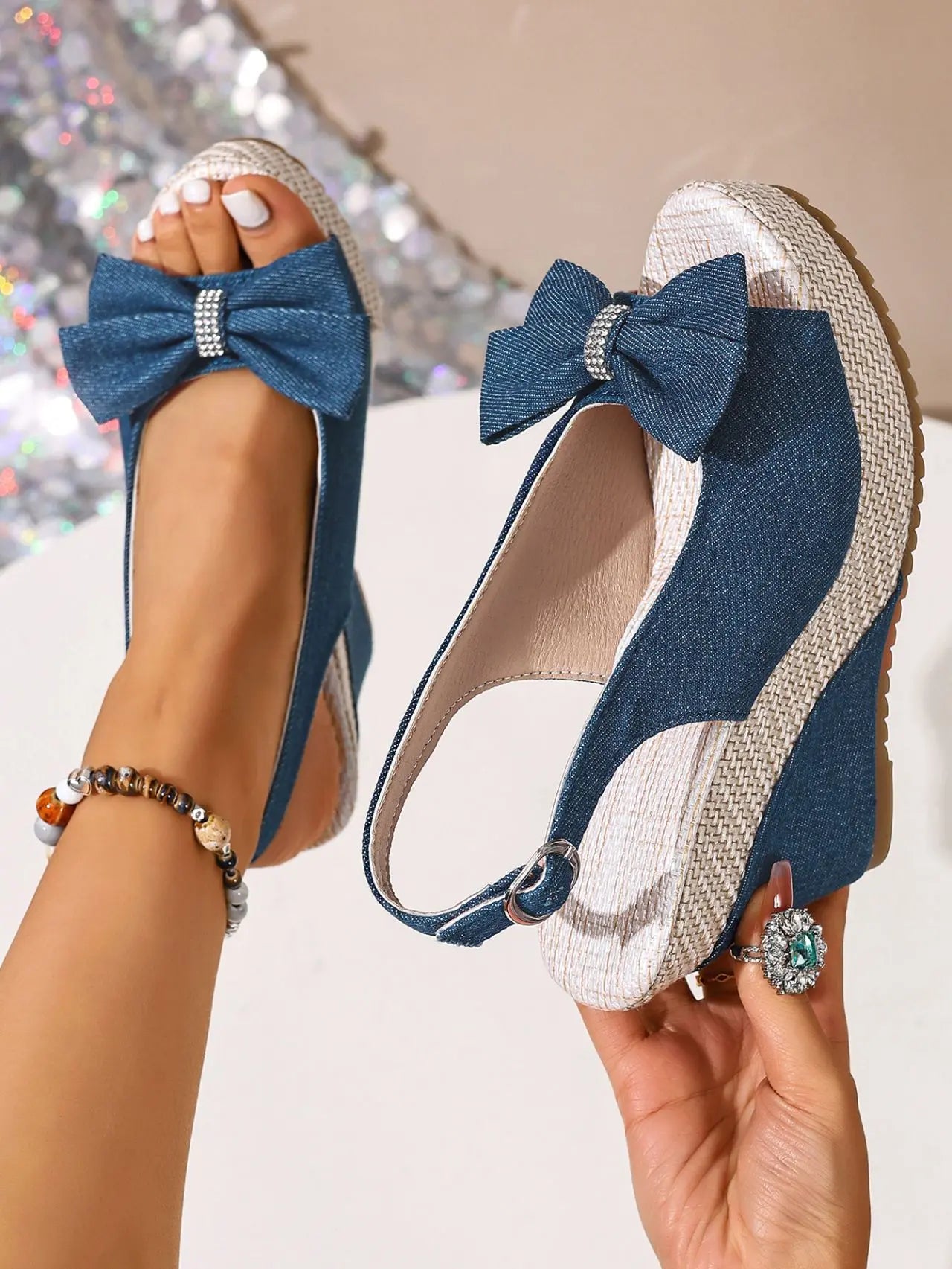 Vykos denim-look wedge sandals with a decorative bow embellished with crystals, featuring an espadrille-wrapped wedge heel and an adjustable slingback strap.