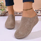 A pair of women's Vylos comfortable wedge mules in warm khaki, featuring intricate floral perforations, white stitching, and a slip-on design shown on a model's feet.