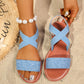 Vytka Roman flat sandals in light blue textured fabric with criss-cross elasticated slingback straps and a silver-tone metal ring embellishment, styled on sand with beach accessories.