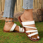 Lifestyle shot of white braided strap summer slide sandals on a woman's feet, styled with distressed denim jeans and a turquoise anklet, set against a natural outdoor backdrop.