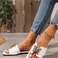 Model's feet wearing Aethel white flat slide sandals featuring a striking gold butterfly embellishment with crystal accents and a square toe, styled with blue jeans and a delicate gold anklet.