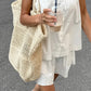 Woman wearing a crisp white 100% cotton camisole and shorts set, featuring a square neck cami with button details and spaghetti straps, styled casually outdoors with a large straw tote bag and a refreshing drink.