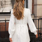 Back view of a white cotton linen mini dress featuring voluminous lantern sleeves, a cinched self-tie belt, and a delicate pom-pom trim along the hem.