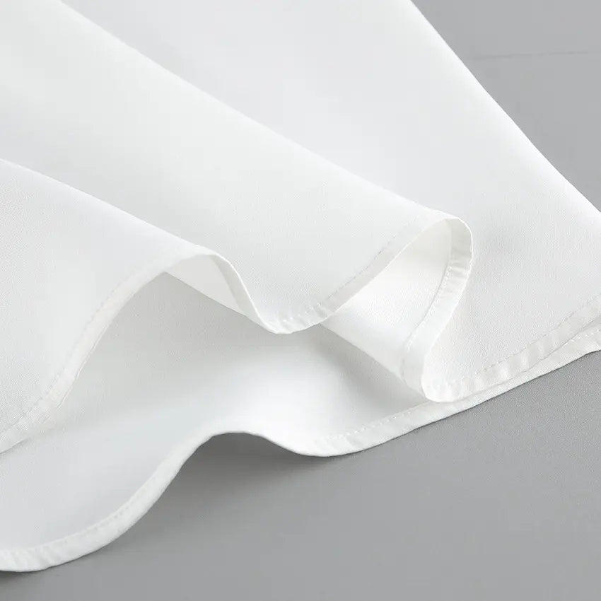 Close-up view of the crisp white matte fabric from an elegant two-piece set, showcasing smooth texture, delicate stitching, and soft pleats.