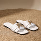 White flat slide sandals for women, featuring a square toe and a single wide strap adorned with an intricate gold-tone metal butterfly embellishment accented with crystals.