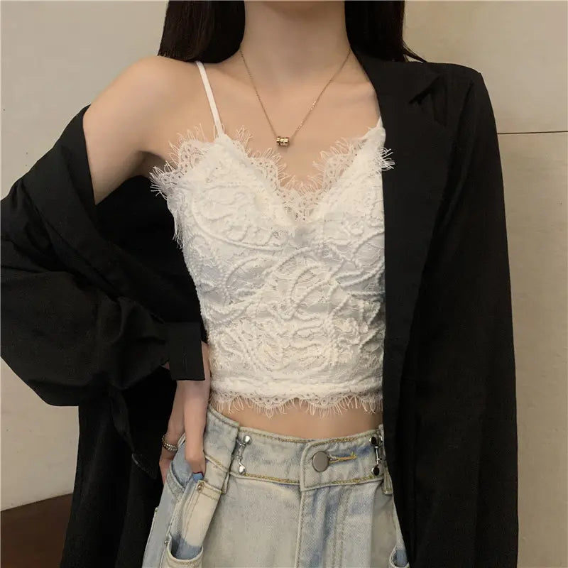 White floral lace cropped camisole with delicate V-neck, eyelash trim, and thin spaghetti straps, worn by a woman under a black blazer.