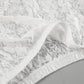 Close-up of intricate white floral lace fabric from a maxi skirt, showcasing the delicate pattern and sheer texture.