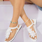 White flat thong sandals adorned with delicate layered lace floral embellishments and a comfortable white elasticated ankle strap.