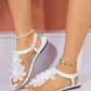 White bohemian thong sandals with delicate layered floral lace embellishments and an elasticated ankle strap, shown on feet with Anklets.