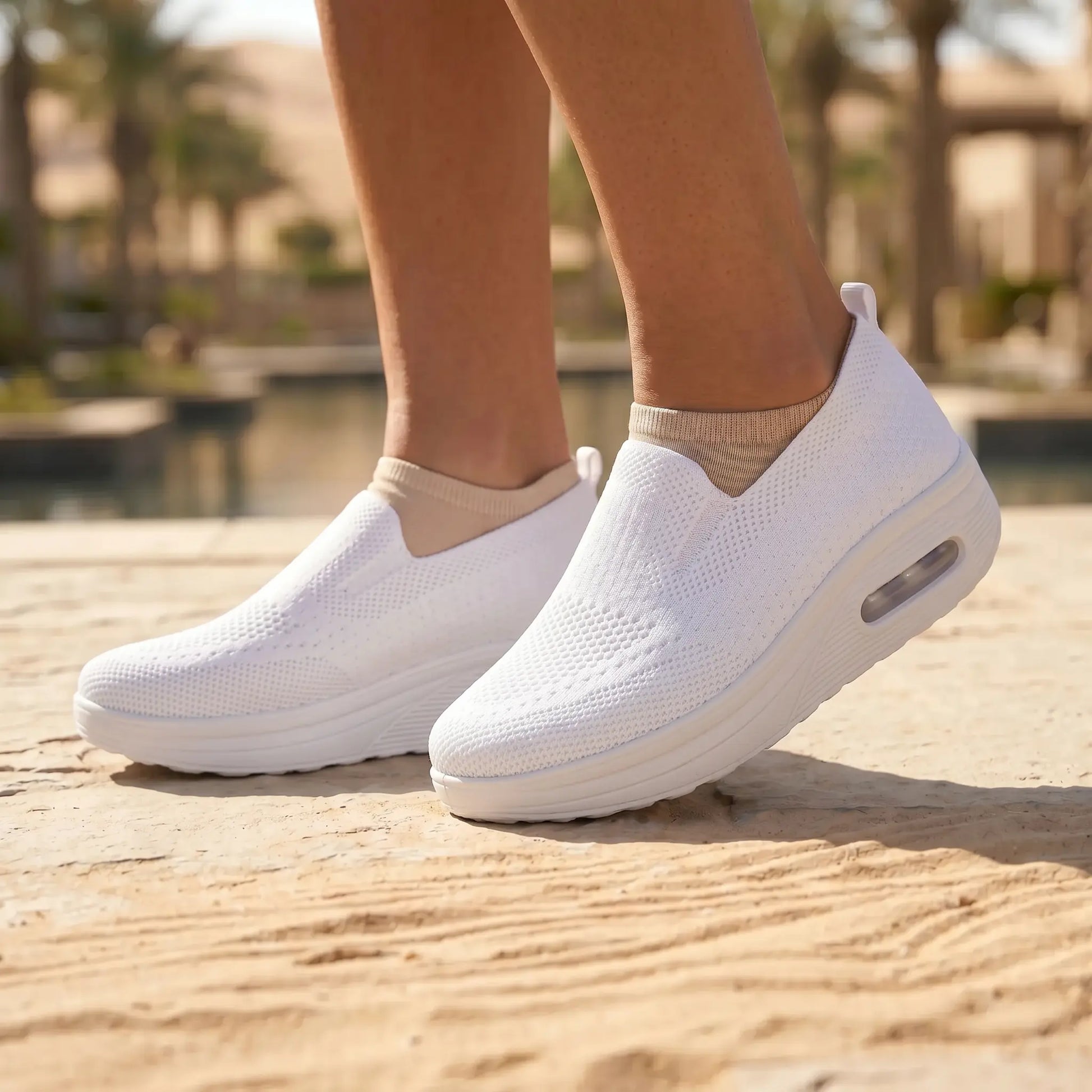 White Myrkos slip-on knit platform sneakers worn on feet, showing the textured upper and visible air cushion heel in an outdoor setting.