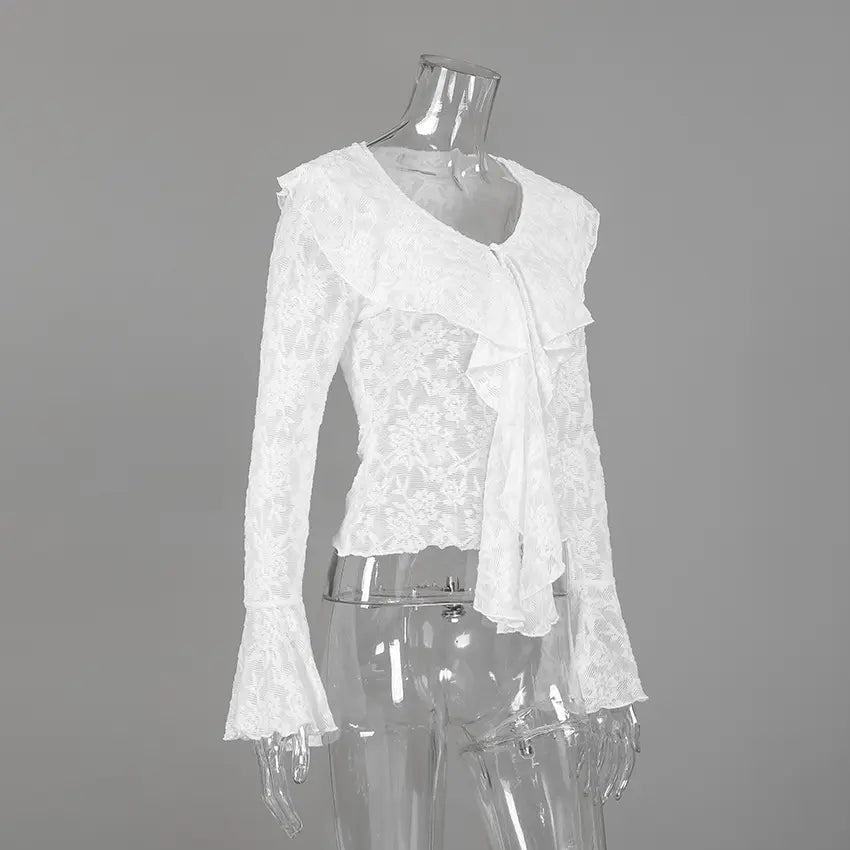 A white sheer floral lace blouse featuring a V-neckline with a cascading ruffle front and dramatic flared bell sleeves, displayed on a clear mannequin against a studio grey background.