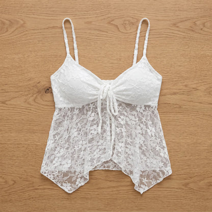 White floral lace camisole with adjustable spaghetti straps and a tie-front detail, shown flat-lay on a wooden surface.