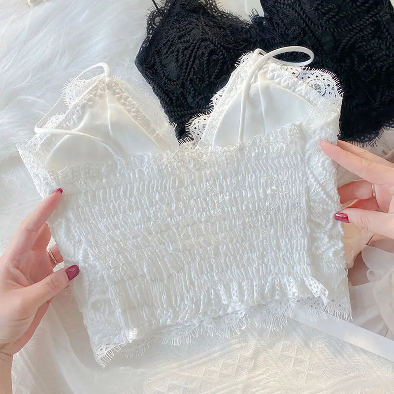 White Zyrin floral lace cropped camisole, highlighting its smocked back panel and delicate eyelash trim. A black camisole variant is partially shown.